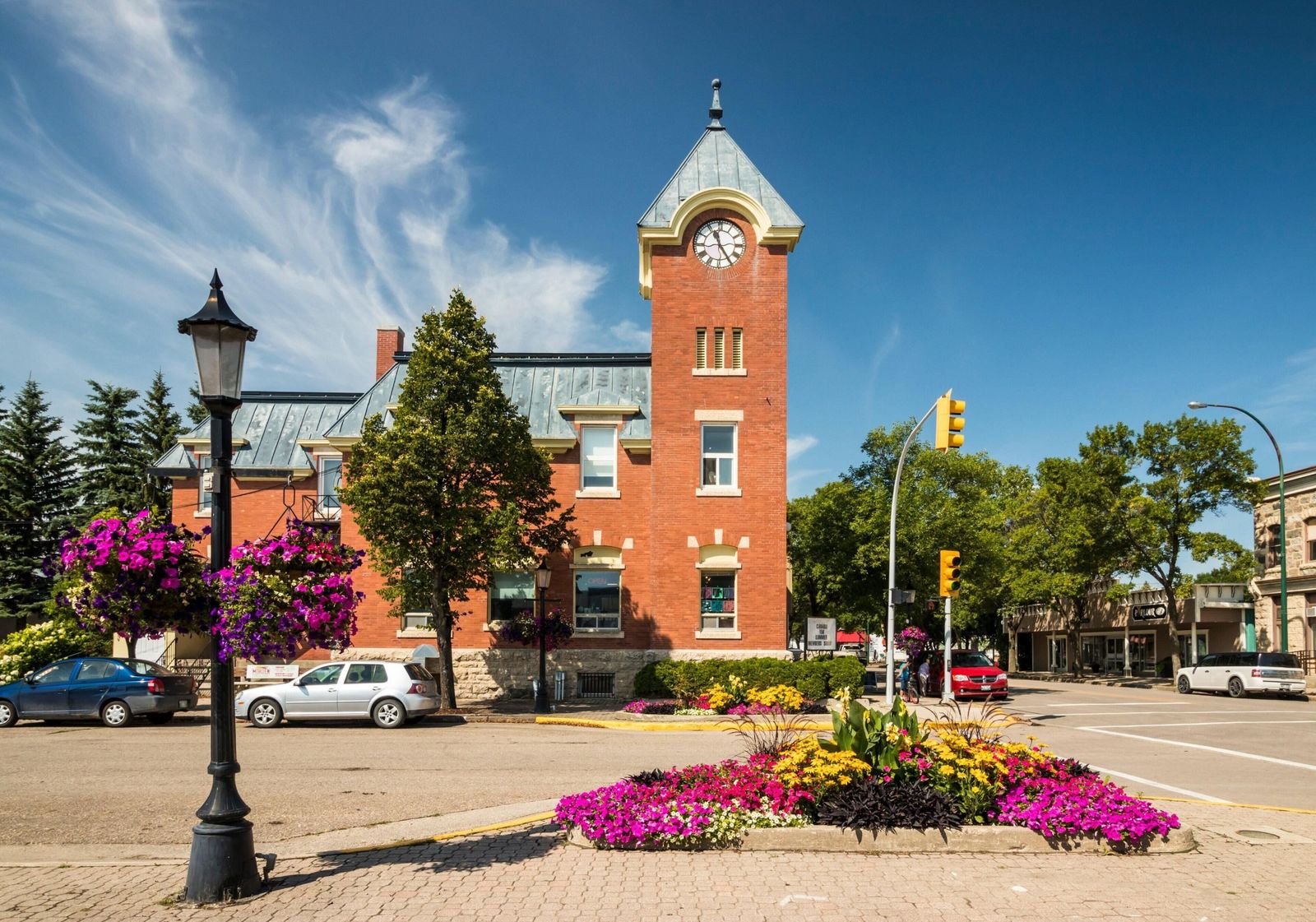 Historic red-brick clock tower building and flower beds in downtown Morden